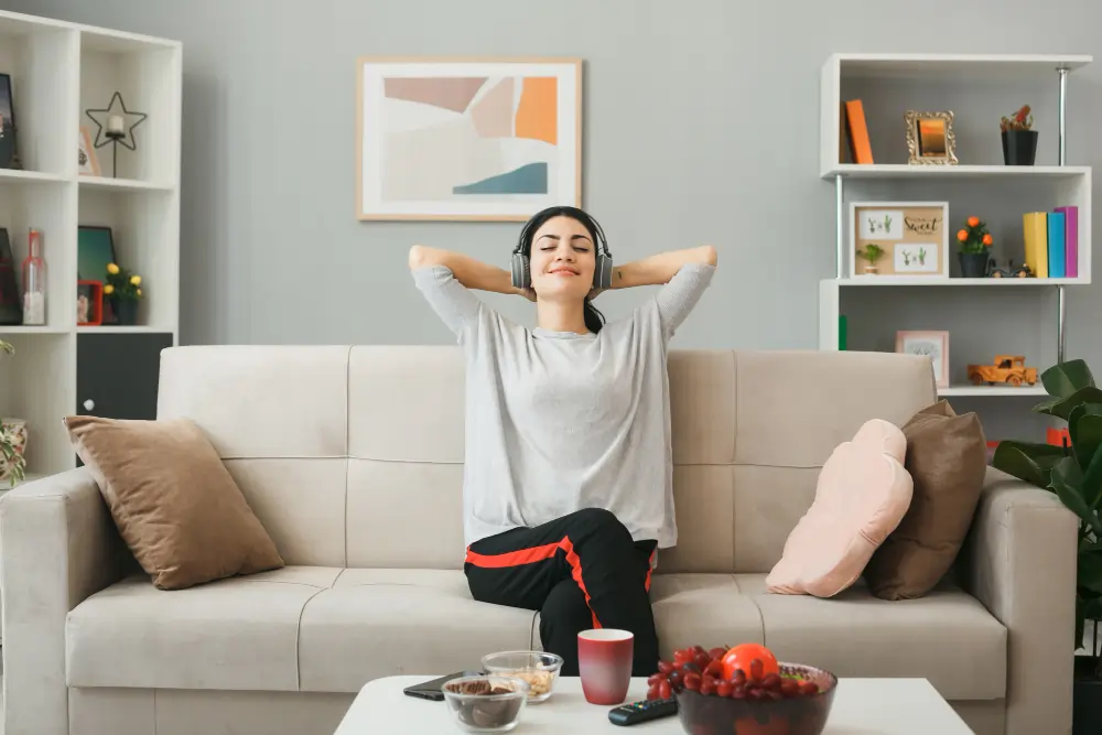 Woman relaxing on a sofa with headphones in a calm home setting, representing everyday comfort wellbeing in Australia through mindful rest, relaxation, and balanced lifestyle habits for overall wellbeing.