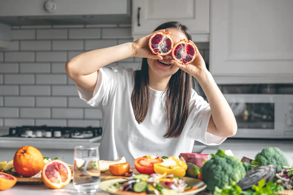 Woman enjoying colourful fruits and vegetables in a kitchen, illustrating the Anti-Inflammatory Diet Australia for comfort.