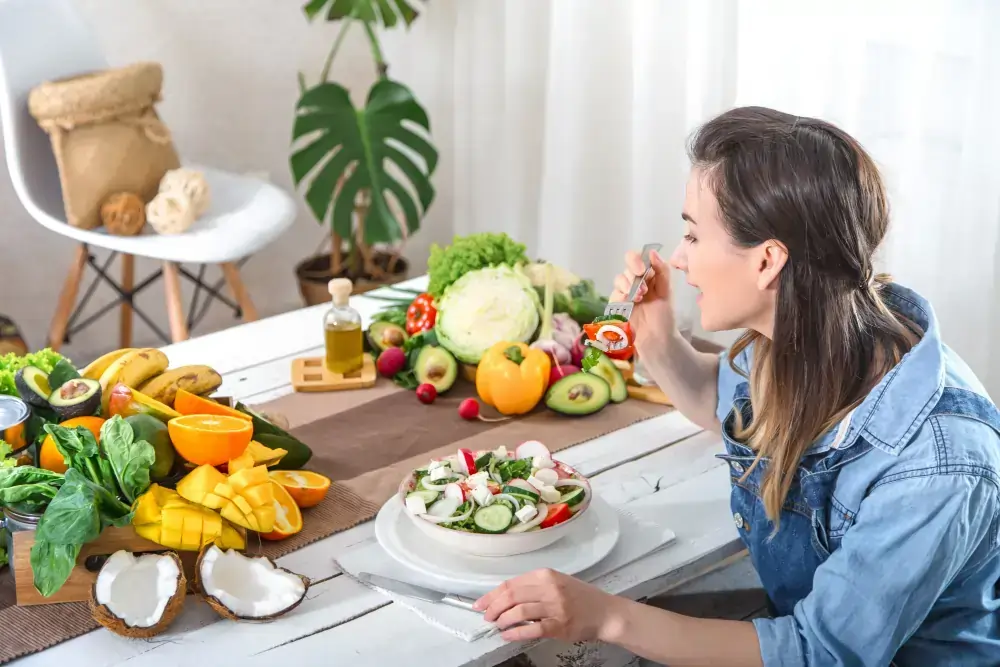 A woman eating a colourful salad surrounded by fresh whole foods that support mood, healthy eating, and emotional wellbeing in Australia.