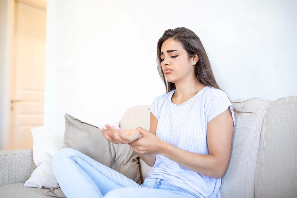 Woman experiencing neuropathic pain symptoms with discomfort in her hand, showing the impact of nerve-related pain and sensitivity in daily life