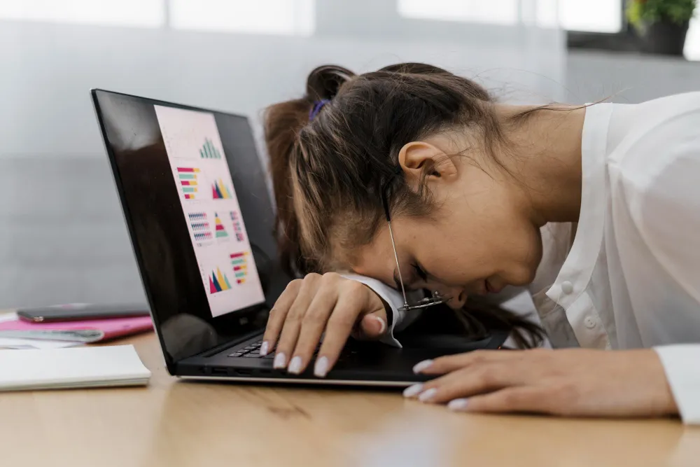 Person experiencing fatigue and difficulty focusing while working on a laptop, representing ADHD challenges and statistics in Australia