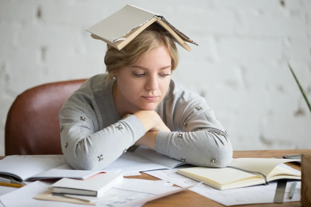 Student with ADHD feeling overwhelmed while studying at a desk with books and notes, representing university challenges, focus difficulties, and study strategies.