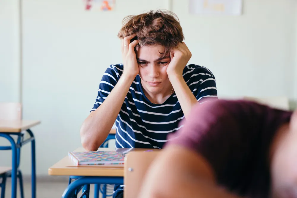 Teenager showing signs of stress during an ADHD assessment process in a classroom setting with focus difficulties.