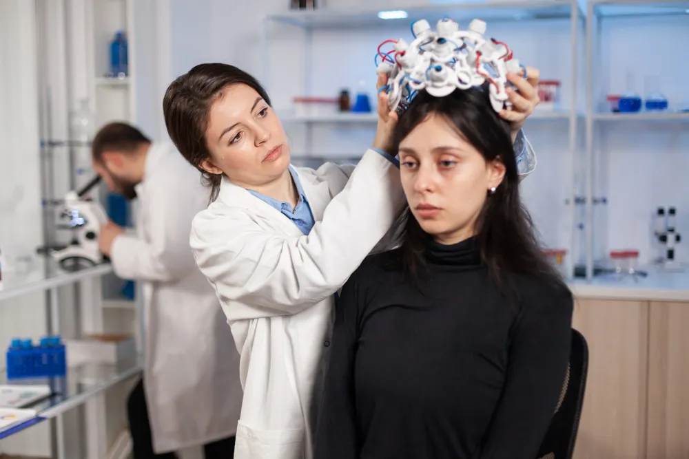 Doctor using EEG brain monitoring equipment to research ADHD causes related to genetics, brain development, and environment.