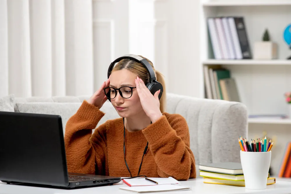 Woman with headphones looking frustrated while taking an online ADHD test on her laptop